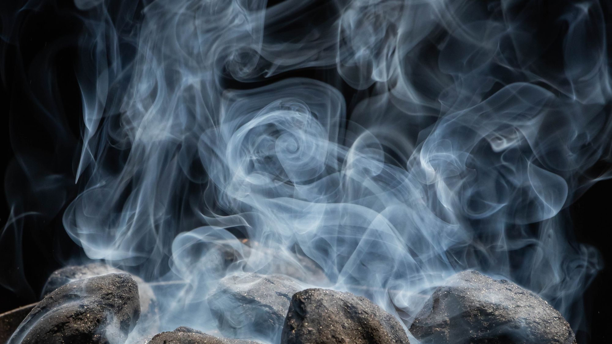 Hardwood charcoal igniting, glowing embers and smoke